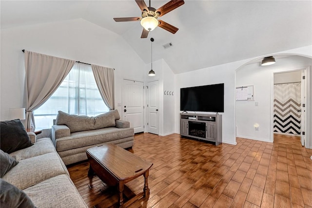 living room featuring ceiling fan, arched walkways, high vaulted ceiling, baseboards, and visible vents
