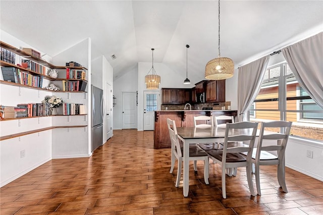 dining space featuring high vaulted ceiling, a chandelier, and wood finished floors