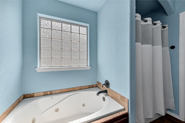 full bath with plenty of natural light, a tub with jets, and a shower with curtain