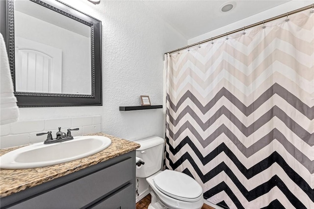 bathroom featuring a textured wall, vanity, toilet, decorative backsplash, and curtained shower