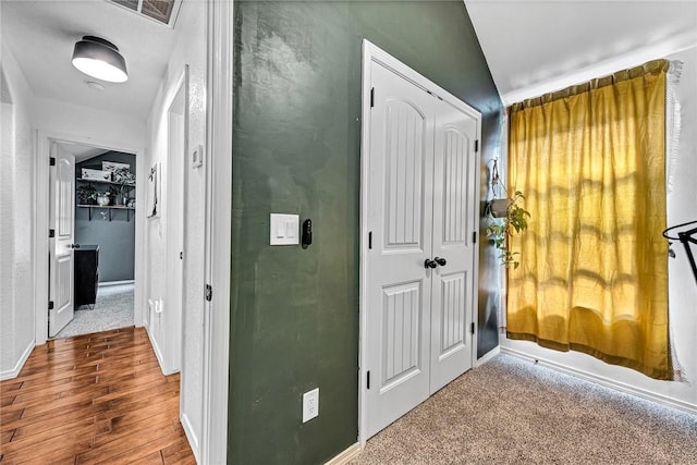 corridor with visible vents, baseboards, and wood finished floors