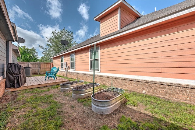 view of yard featuring fence, a wooden deck, and central AC