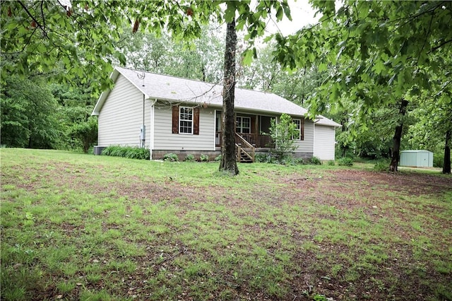view of front facade featuring a storage shed, an outbuilding, a shingled roof, and a front lawn