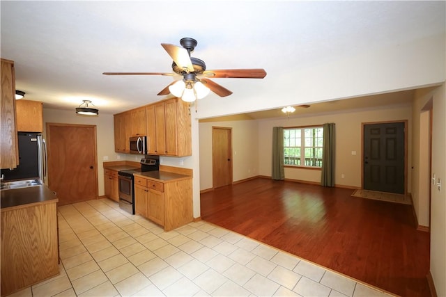 kitchen with appliances with stainless steel finishes, a sink, light wood-style floors, a ceiling fan, and open floor plan