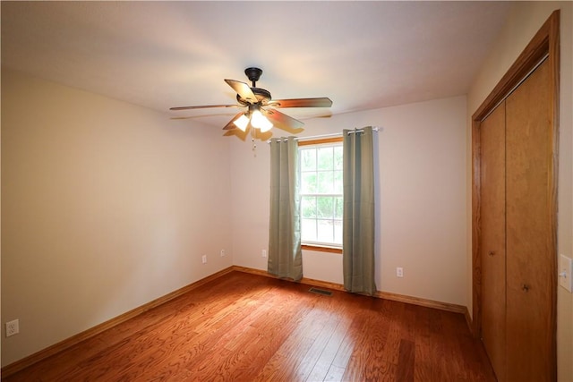 unfurnished bedroom with ceiling fan, baseboards, light wood-type flooring, visible vents, and a closet