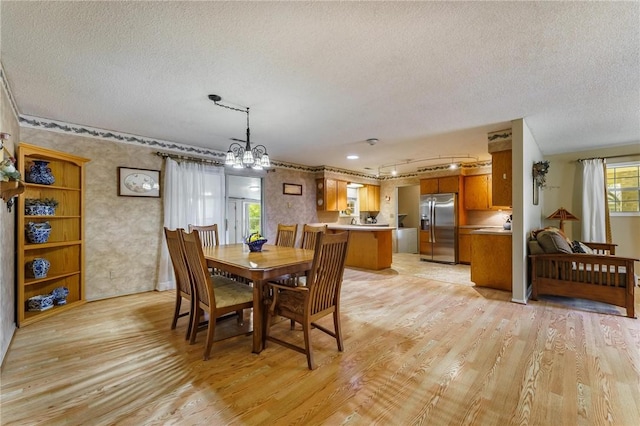 dining room with a textured ceiling, track lighting, and light wood-type flooring