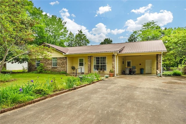 single story home with driveway, metal roof, a front lawn, and an attached carport