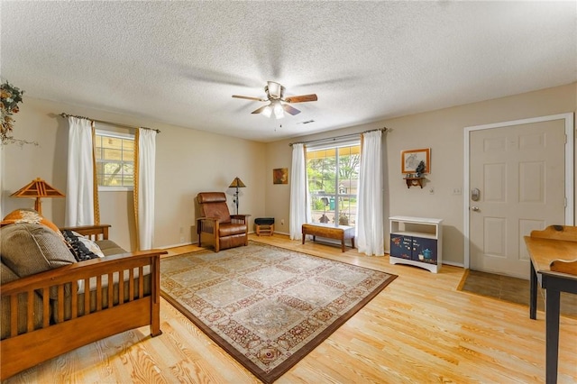 bedroom with ceiling fan, light wood finished floors, and a textured ceiling