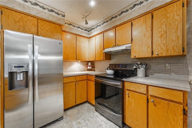 kitchen with under cabinet range hood, stainless steel appliances, decorative backsplash, and light countertops