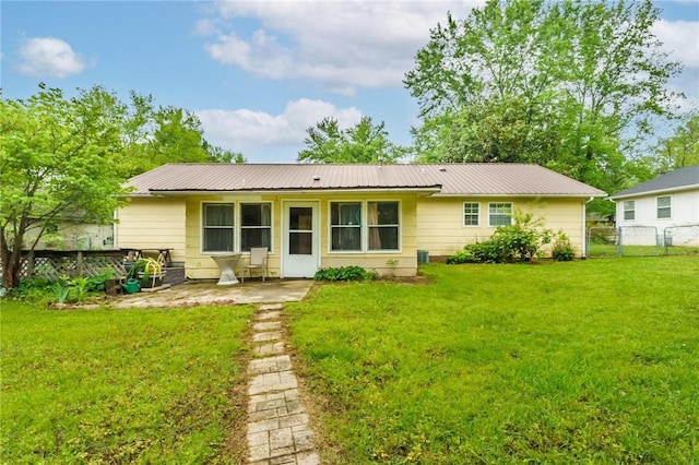 rear view of property featuring a lawn, a patio area, fence, and metal roof