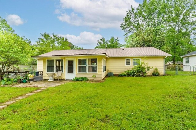 back of property featuring central AC, fence, a patio, metal roof, and a lawn