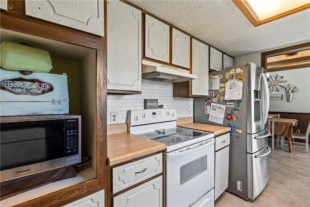 kitchen with a textured ceiling, stainless steel appliances, backsplash, light tile patterned floors, and under cabinet range hood