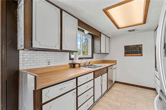 kitchen with baseboards, light countertops, tasteful backsplash, a sink, and stainless steel appliances