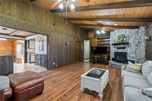 living area with ceiling fan, wood finished floors, wooden walls, and beam ceiling