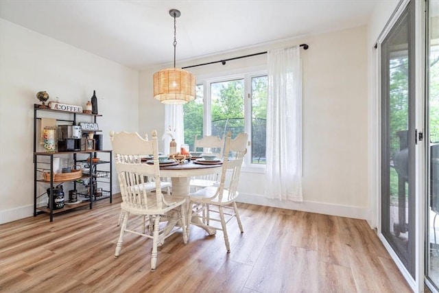 dining space with baseboards and light wood-style flooring