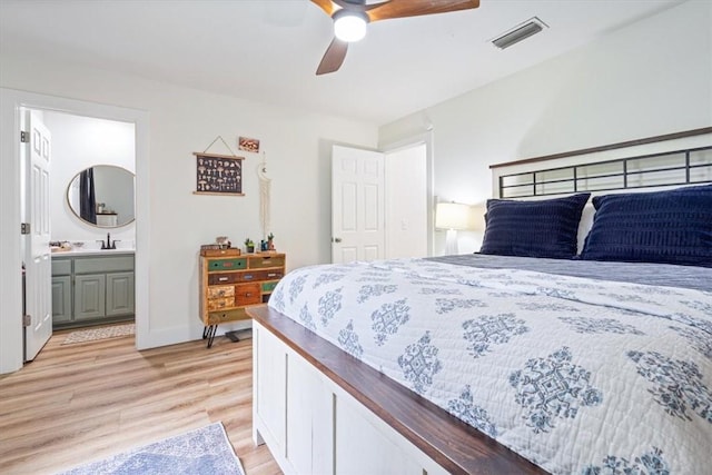 bedroom with ceiling fan, a sink, light wood finished floors, ensuite bath, and visible vents