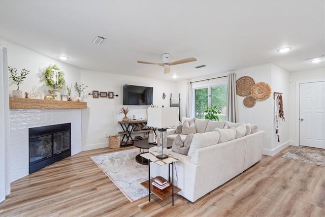 living area featuring recessed lighting, a ceiling fan, light wood finished floors, and a glass covered fireplace