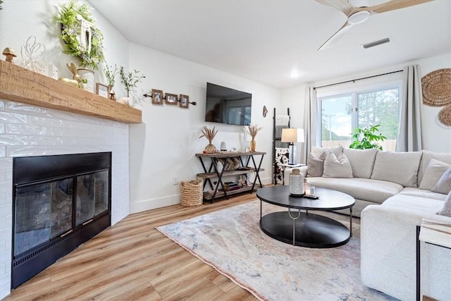 living area featuring a glass covered fireplace, recessed lighting, baseboards, wood finished floors, and visible vents