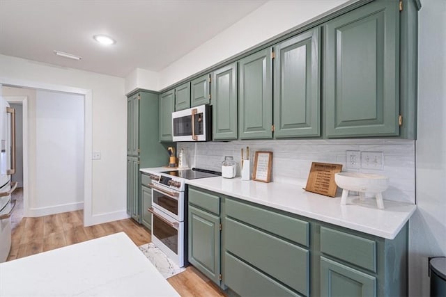 kitchen featuring light countertops, range with two ovens, green cabinetry, and decorative backsplash