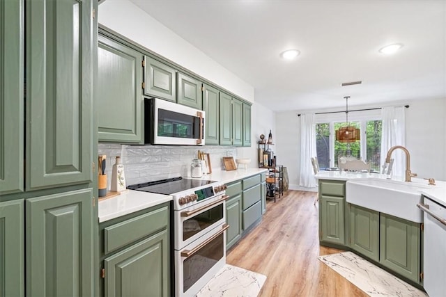 kitchen featuring tasteful backsplash, a sink, white appliances, light wood-type flooring, and green cabinets