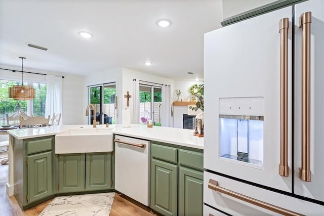 kitchen with visible vents, green cabinets, a sink, and white appliances