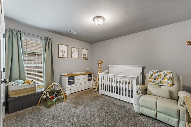 carpeted bedroom featuring visible vents and a nursery area