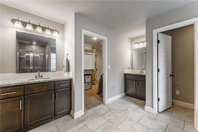 full bathroom featuring a sink, baseboards, a shower stall, and two vanities