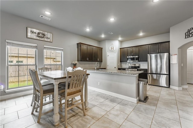 kitchen with light tile patterned floors, appliances with stainless steel finishes, dark brown cabinetry, and visible vents