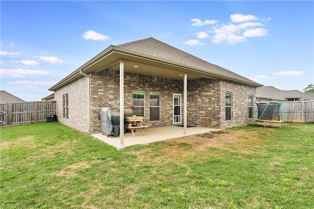 back of house featuring a patio, a fenced backyard, a trampoline, and brick siding