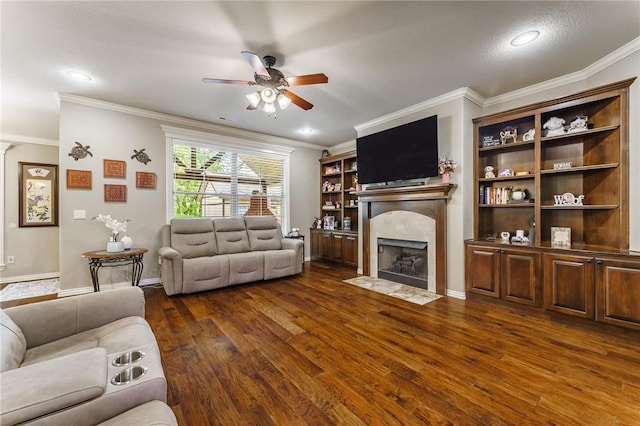 living room featuring crown molding, a ceiling fan, dark wood finished floors, and a tiled fireplace