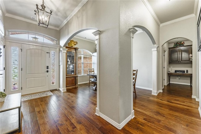 entryway with arched walkways, decorative columns, dark wood-style floors, and a chandelier