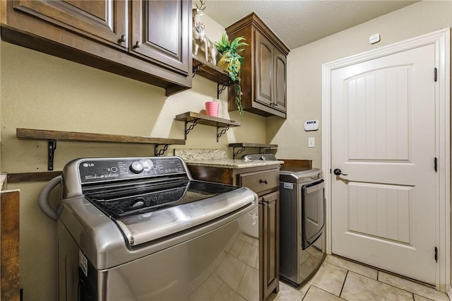 washroom with light tile patterned flooring, cabinet space, and washer and clothes dryer