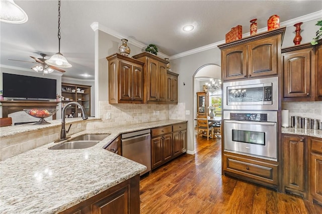 kitchen featuring appliances with stainless steel finishes, light stone counters, a sink, backsplash, and ornamental molding