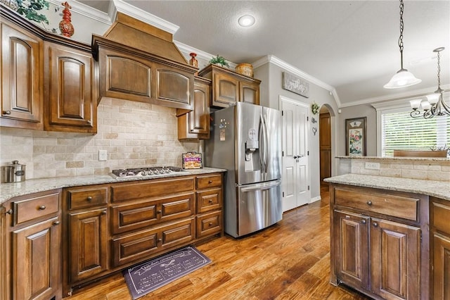 kitchen with ornamental molding, decorative backsplash, wood finished floors, arched walkways, and stainless steel appliances