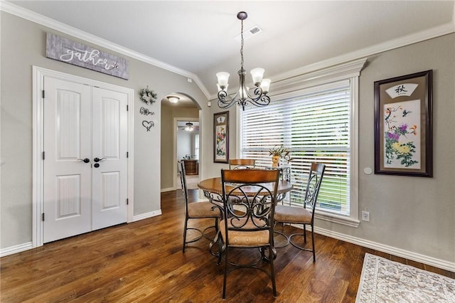 dining room with crown molding, baseboards, arched walkways, and dark wood-type flooring