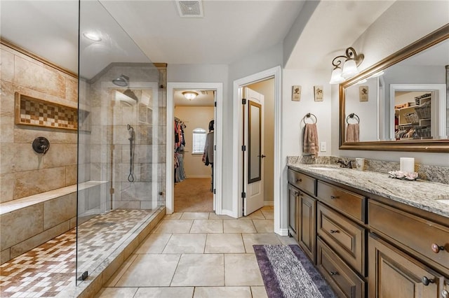 bathroom featuring double vanity, a walk in closet, visible vents, a sink, and a walk in shower