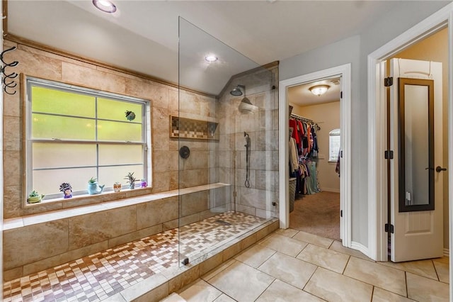 full bath with tile patterned floors, vaulted ceiling, a walk in closet, and a stall shower