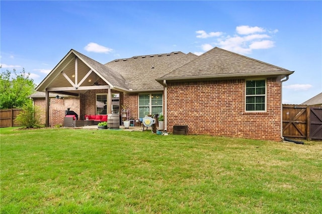 rear view of property with a yard, brick siding, and a fenced backyard