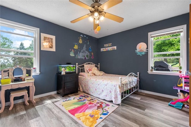 bedroom featuring a ceiling fan, baseboards, wood finished floors, and a textured ceiling