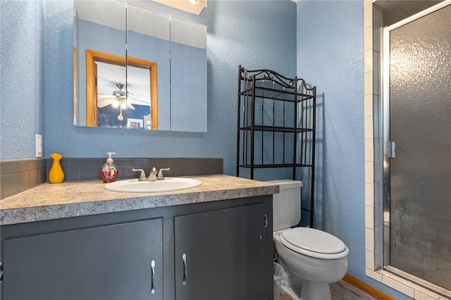 bathroom with vanity, a textured wall, a stall shower, and toilet
