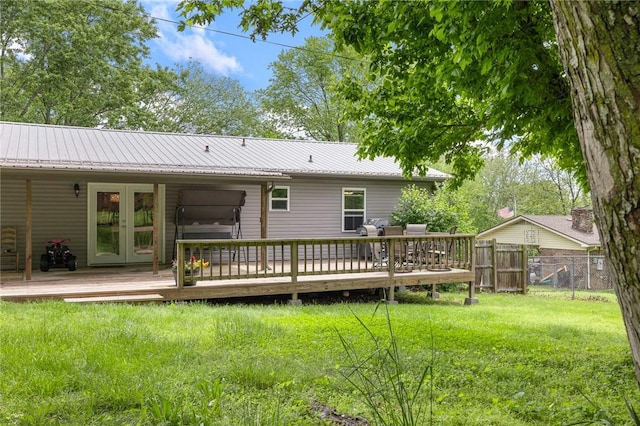 back of property featuring french doors, metal roof, a lawn, a wooden deck, and fence