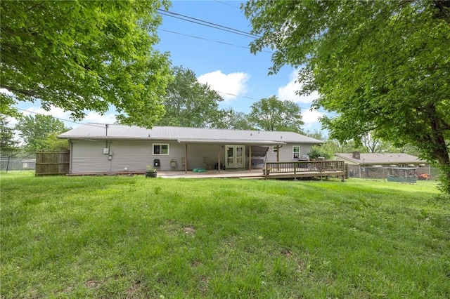 back of house with french doors, metal roof, a lawn, a wooden deck, and fence