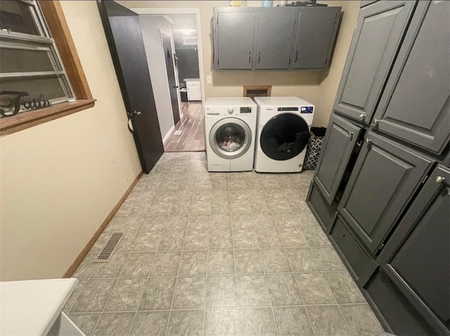 washroom with cabinet space, baseboards, visible vents, and washer and clothes dryer