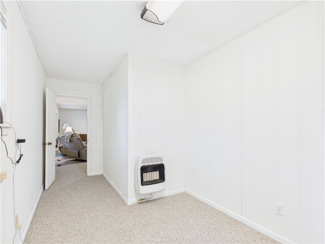 empty room featuring light colored carpet, heating unit, and baseboards