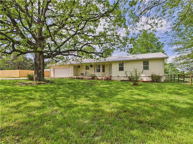 rear view of house with a lawn, an attached garage, and fence