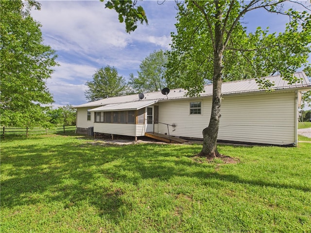 back of property with a sunroom, fence, a yard, and metal roof