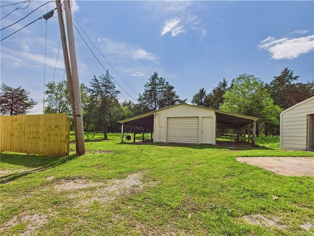 view of yard featuring driveway, fence, an outdoor structure, and a garage