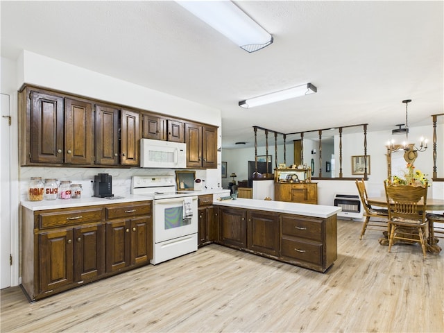 kitchen with light wood-type flooring, light countertops, a peninsula, and white appliances