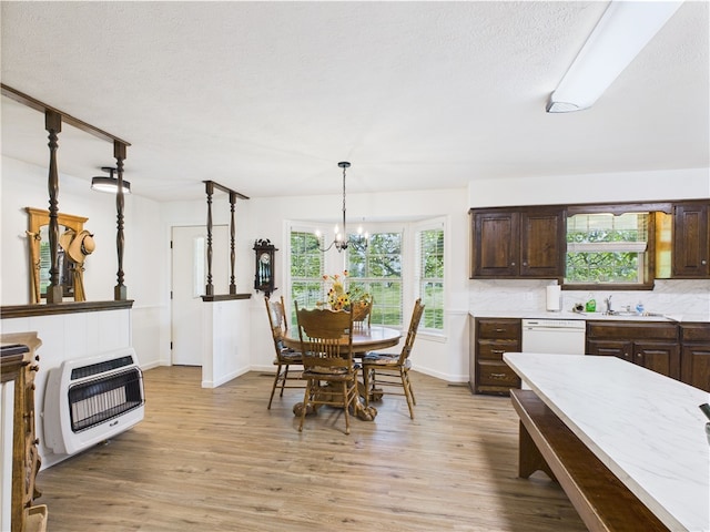 dining space with heating unit, a wealth of natural light, light wood-style flooring, and a notable chandelier