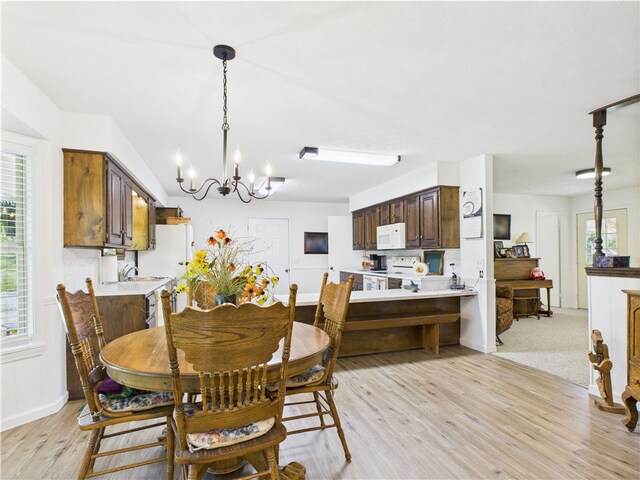 dining area featuring baseboards, an inviting chandelier, a healthy amount of sunlight, and light wood-type flooring
